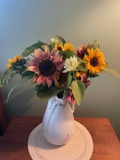 Sunflowers and garden blooms arranged in a white pitcher